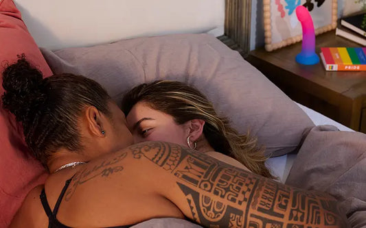 Queer lesbian couple laughing and cuddling in bed